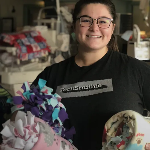 TechSmith employee holding blankets to donate
